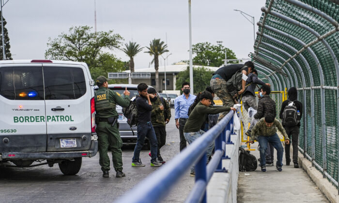 A Border Patrol agent drops a group of illegal immigrants being expelled under Title 42 at the halfway point of the international bridge between the United States and Mexico, in Eagle Pass, Texas, on April 19, 2022. (Charlotte Cuthbertson/The Epoch Times)