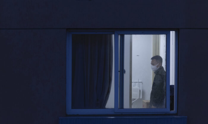2022 年 4 月 13 日，一名戴着防护面罩的男子在中国上海一个住宅区的家中的窗户外被看到。（盖蒂图片社/盖蒂图片社）