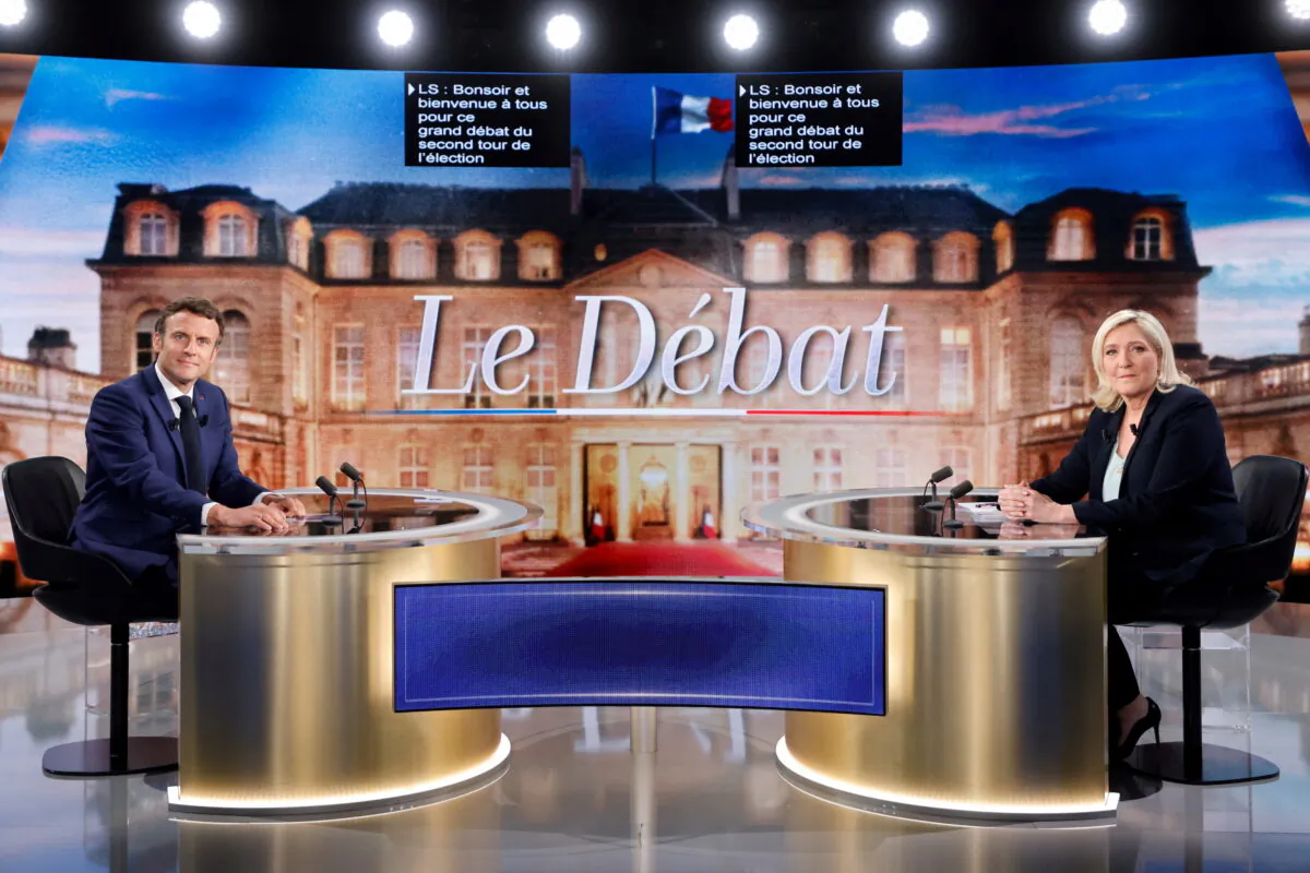 French President Emmanuel Macron (L), candidate for his reelection, and Rassemblement National party presidential candidate Marine Le Pen sit prior to taking part in a French presidential election debate, in Saint-Denis, north of Paris, France, on April 20, 2022. (Ludovic Marin/Pool via Reuters)