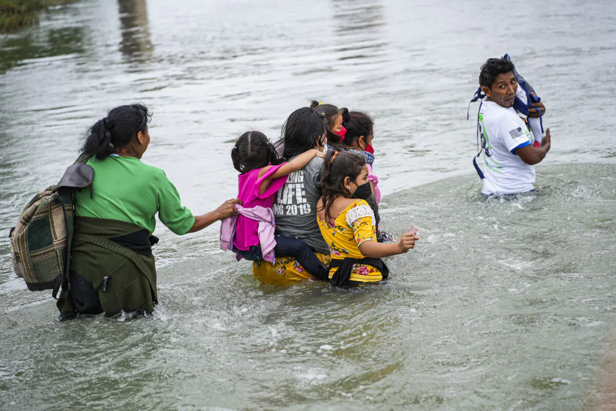 A group of Hondurans cross the Rio Grande toward Eagle Pass, Texas, from Piedras Negras, Mexico, on April 21, 2022. (Charlotte Cuthbertson/The Epoch Times)