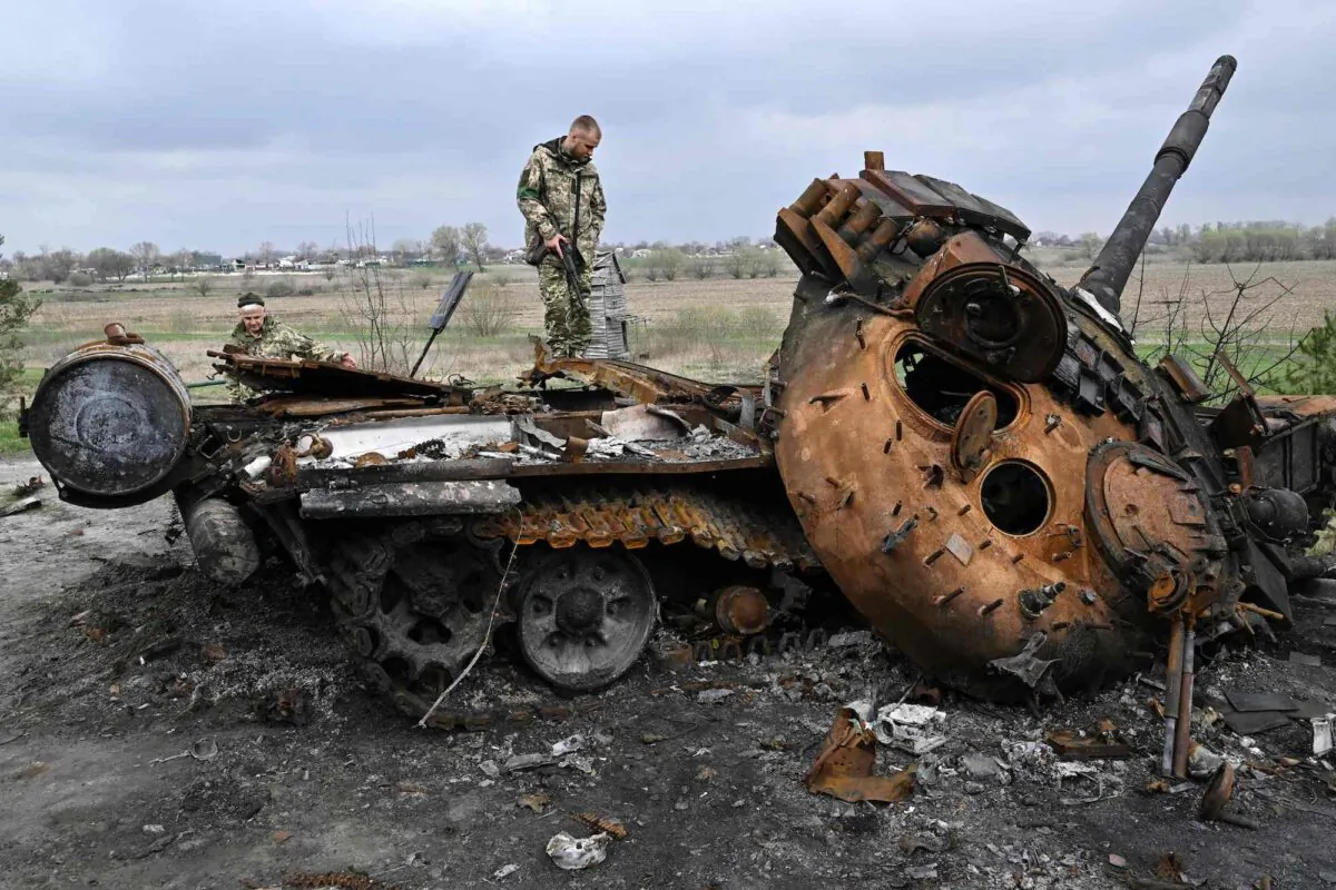 Ukrainian servicemen look at a destroyed Russian tank on a road in the village of Rusaniv, near Kyiv, Ukraine, on April 16, 2022. (Genya Savilov/AFP/Getty Images)