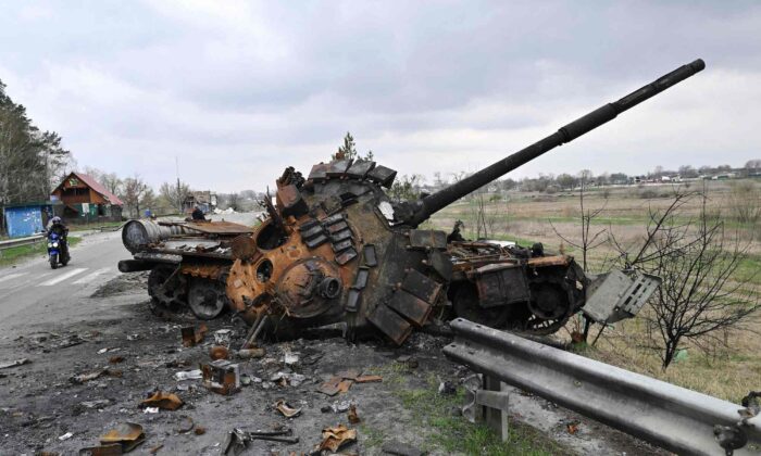 A man rides a motorbike past a destroyed Russian tank on a road in the village of Rusaniv, near Kyiv, Ukraine, on April 16, 2022. (Genya Savilov/AFP/Getty Images)