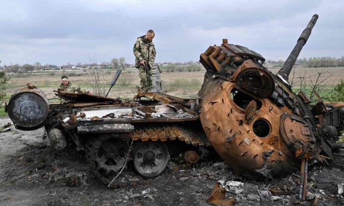 Ukrainian servicemen look at a destroyed Russian tank on a road in the village of Rusaniv, near Kyiv, Ukraine, on April 16, 2022. (Genya Savilov/AFP/Getty Images)