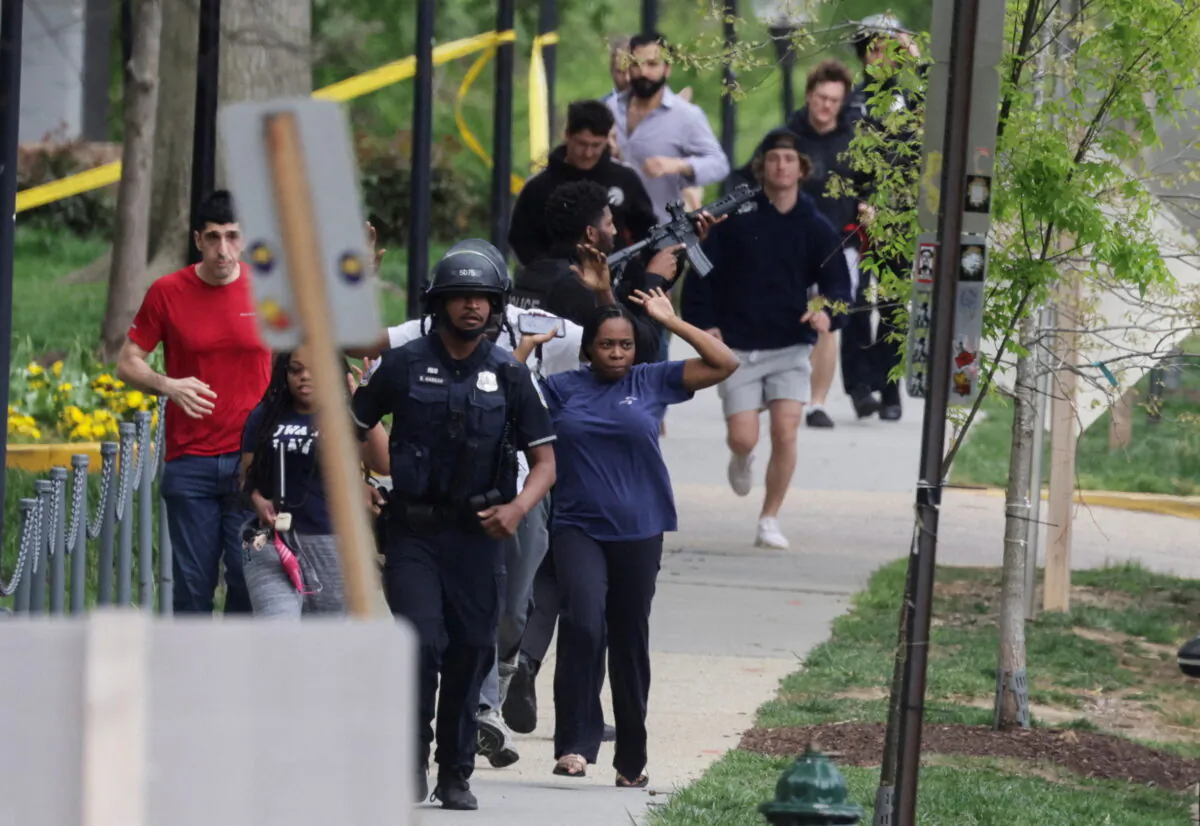 Washington, Metropolitan Police officers run with civilians while one of the officers keeps his weapon trained on a nearby building as police evacuate people to safety at the scene of a reported shooting and active shooter near Edmund Burke Middle School in the Cleveland Park neighborhood of Northwest Washington, on April 22, 2022. (Evelyn Hockstein/Reuters)