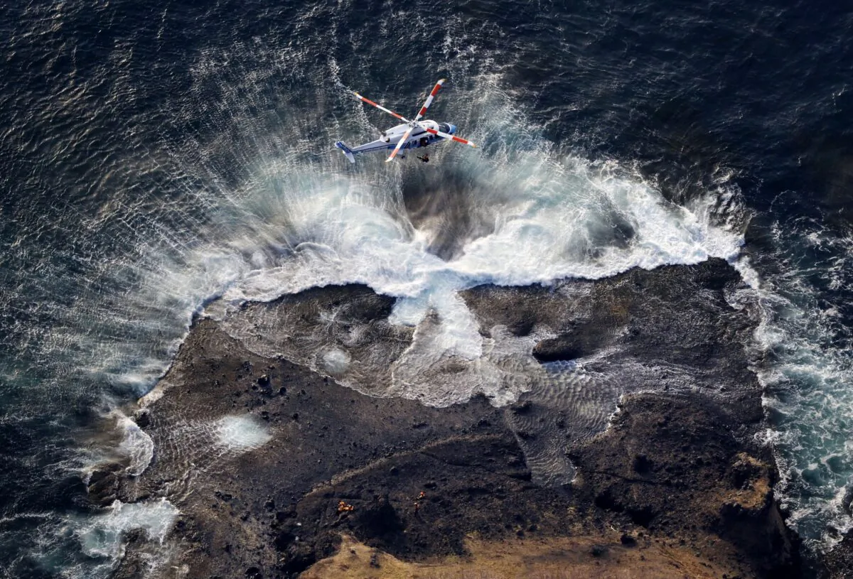 A rescuer being lifted in a search operation for missing passengers and crew members of a sunken tour boat off Shiretoko Peninsula, northern Japan of Hokkaido, on April 24, 2022. (Masanori Takei/Kyodo News via AP)