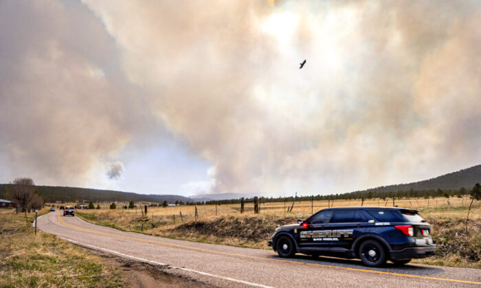 San Miguel County Sheriff's Officers patrol NM94 near Penasco Blanco as the Calf Fire burns nearby, on April 22, 2022. (Eddie Moore/The Albuquerque Journal via AP)
