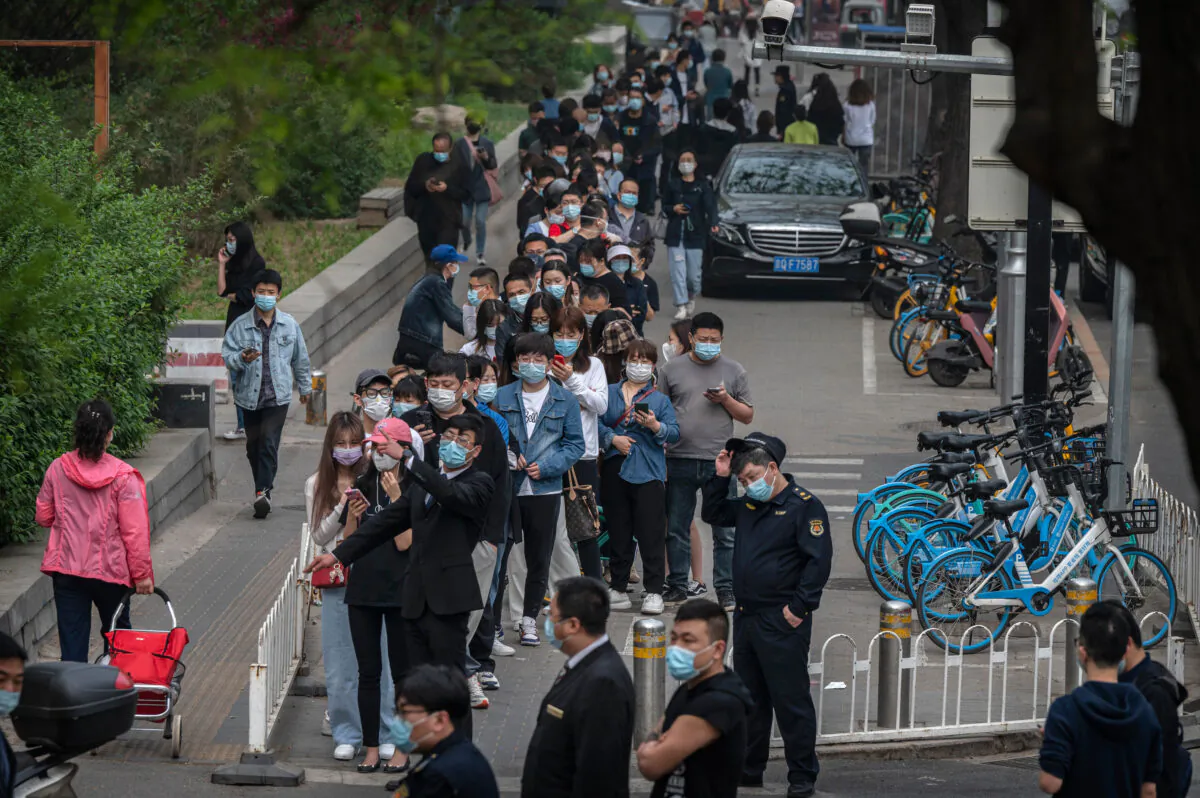 People line up to give a sample for nucleic acid testing for COVID-19 at a makeshift test site in Chaoyang District on April 25, 2022 in Beijing, China. China is trying to contain a spike in coronavirus cases in Beijing after dozens of people tested positive for the virus in recent days, causing local authorities to initiate mass testing in some areas and to lockdown some neighbourhoods in an effort to maintain the country's zero-COVID strategy. (Kevin Frayer/Getty Images)