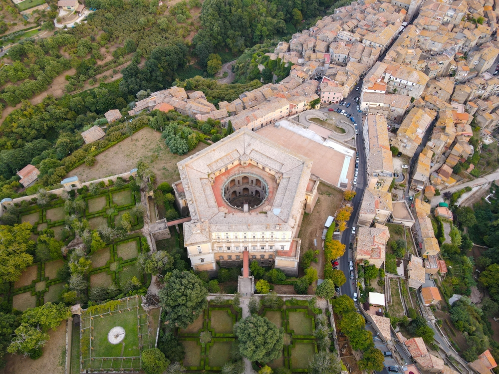 The main road leads to the pentagonal Villa Farnese. The circular courtyard can be seen within and the drawbridges lead across the moat to the parterre renaissance gardens on the left. Parterre gardens are characterized by geometrically formed hedges designed to be viewed from the building. (AerialDronePics/Shutterstock)
