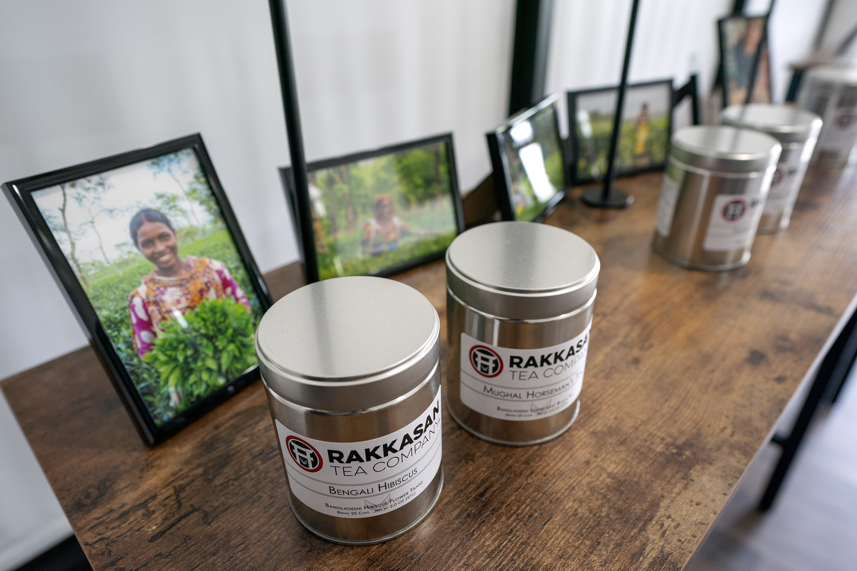 Canisters of Rakkasan Tea sit in front of photos of tea growers from the countries where the tea was sourced .
