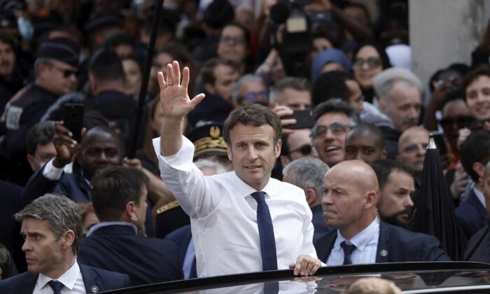 Newly reelected French President Emmanuel Macron waves from his car after his visit at the Saint-Christophe market square in Cergy, a Paris suburb, on April 27, 2022. (Benoit Tessier, Pool via AP)