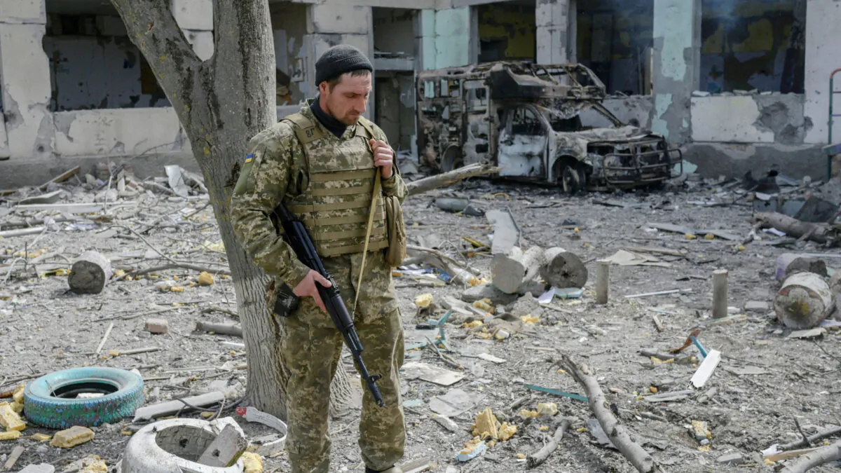 A Ukrainian soldier stands outside a school hit by Russian rockets in the southern Ukraine village of Zelenyi Hai between Kherson and Mykolaiv, less than 5 km from the front line on April 1, 2022. (Bulent Kilic/AFP via Getty Images)