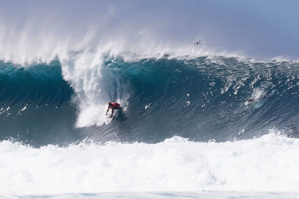 A drone flies above former World Surf League (WSL) Champion John John Florence of Hawaii as he competes in the Billabong Pipeline Masters at Pipeline on the north shore of Oahu, Hawaii, on January 29, 2022. (Photo by BRIAN BIELMANN/AFP via Getty Images)