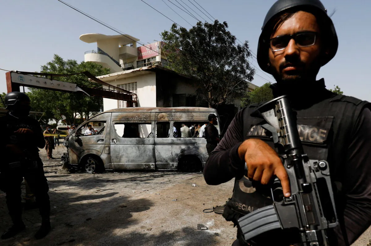 Police officers stand guard near a passenger van, after a blast at the entrance of the Confucius Institute University of Karachi, Pakistan, on April 26, 2022. (Akhtar Soomro/Reuters)