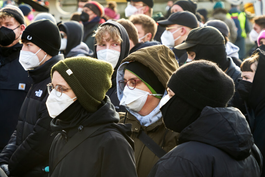 Young people wear masks against the COVID-19 contagion and caps on their heads without distancing at a demonstration against COVID-19 deniers in Braunschweig, Germany, on Jan. 8, 2022. (geogif/Shutterstock)