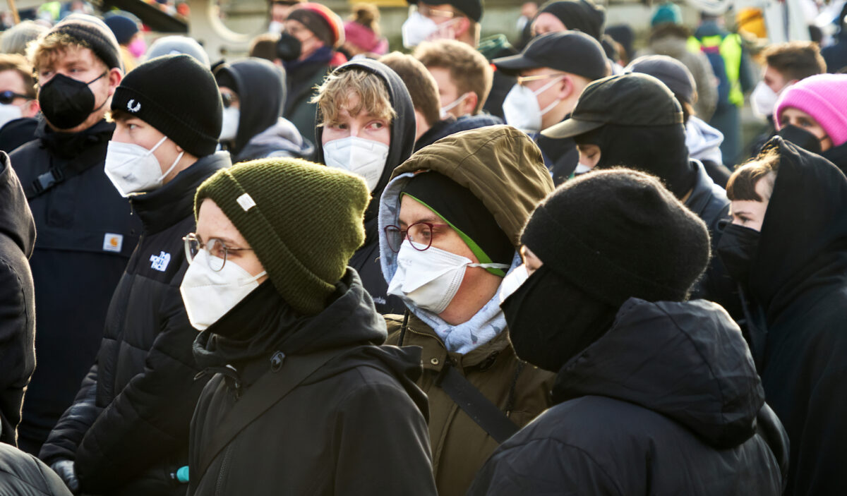 Young people wear masks against the COVID-19 contagion and caps on their heads without distancing at a demonstration against COVID-19 deniers in Braunschweig, Germany, on Jan. 8, 2022. (geogif/Shutterstock)