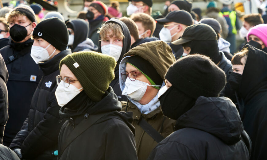 Young people wear masks against the COVID-19 contagion and caps on their heads without distancing at a demonstration against COVID-19 deniers in Braunschweig, Germany, on Jan. 8, 2022. (geogif/Shutterstock)