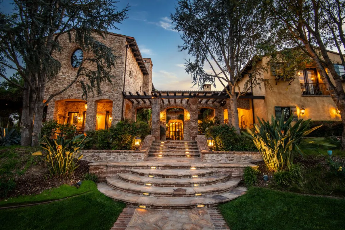 Here you see the meticulous stonework and the trellised loggia that leads to styled glass doors at the entry of the home. As you can see, the home conveys a sense of grandeur, as well as a warm welcoming. (Jade Mills)