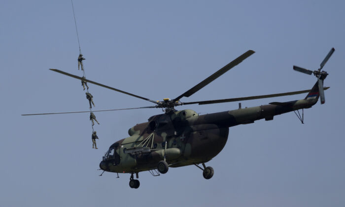 A helicopter flies by Serbian Army soldiers performing during military exercises on a military airport near Belgrade, Serbia, on April 30, 2022. (Darko Vojinovic/AP Photo)