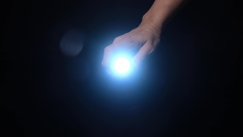 A,Hand,Holding,A,Led,Flashlight,With,Blue,Beam,And