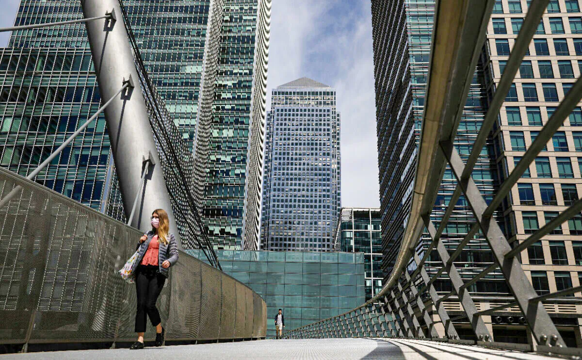 A woman wearing a mask crossing a bridge in front of One Canada Square in Canary Wharf, following the outbreak of the CCP virus in London on May 18, 2020. (Simon Dawson/Reuters)