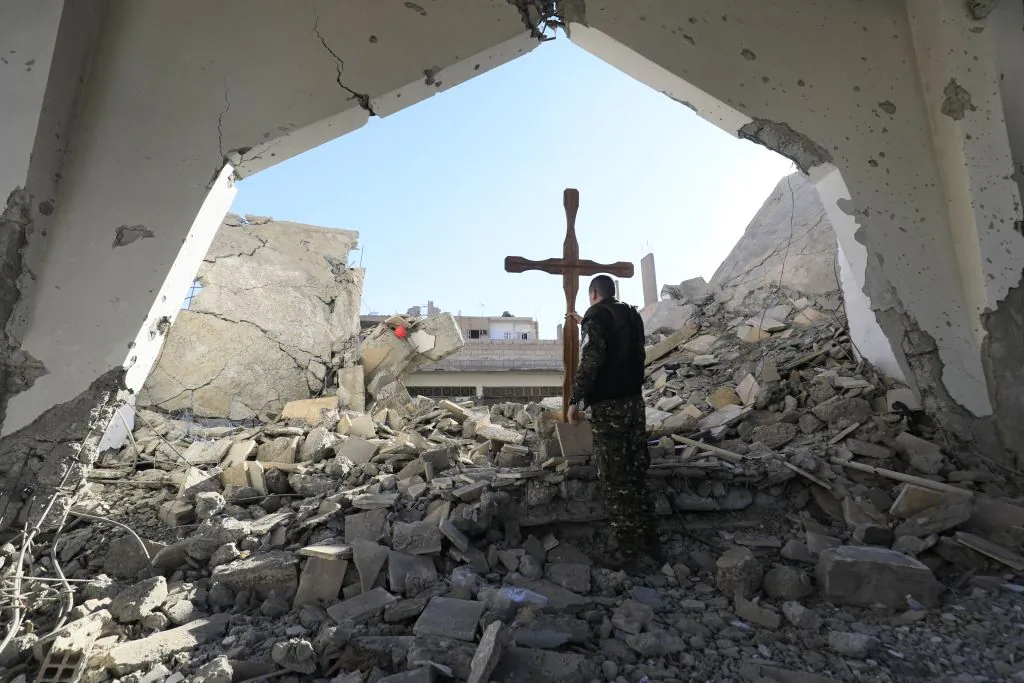 A member of the Syrian Arab-Kurdish forces places a cross in the rubble ahead of a Christmas celebration at the heavily-damaged Armenian Catholic Church of the Martyrs in the city centre of the eastern Syrian city of Raqa on Dec. 26, 2017. (Delil Souleiman/AFP via Getty Images)
