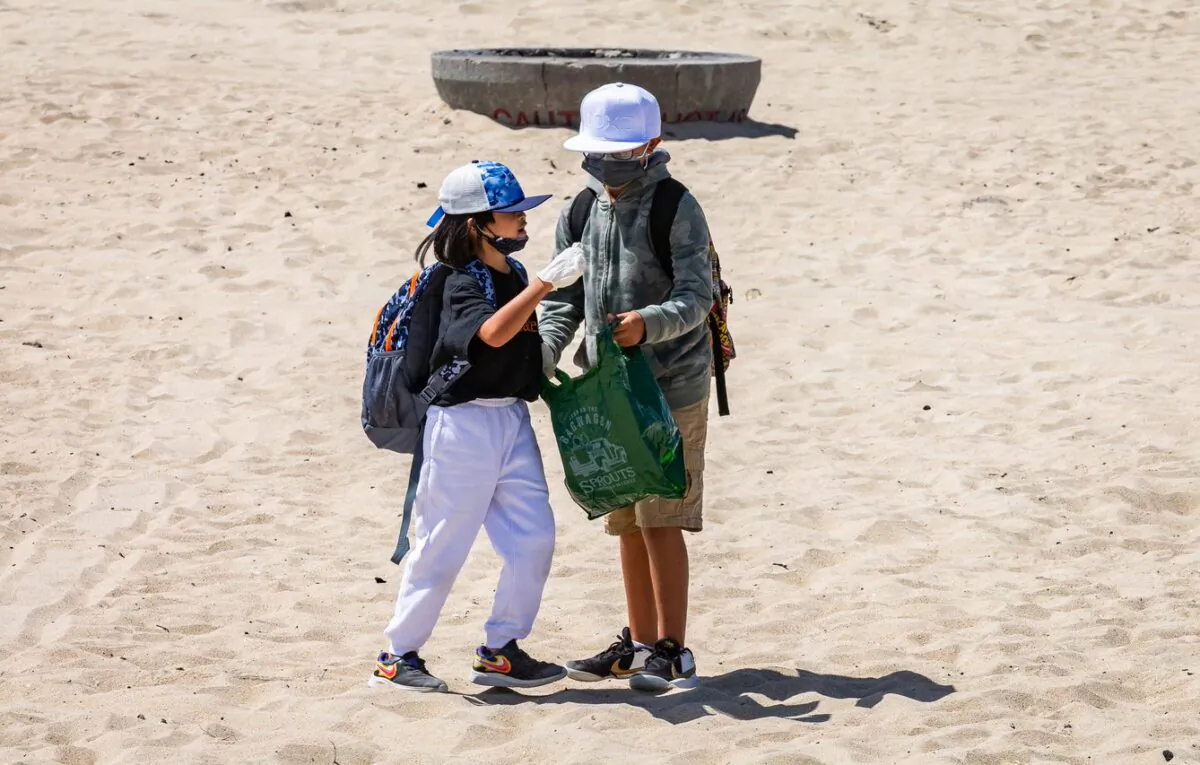 Elementary school students celebrating Kids Ocean Day work together in cleaning Huntington State Beach in Huntington Beach, Calif., on May 31, 2022. (John Fredricks/The Epoch Times)