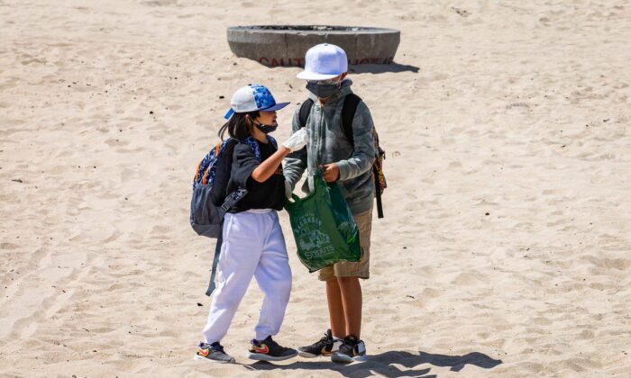 Elementary school students celebrating Kids Ocean Day work together in cleaning Huntington State Beach in Huntington Beach, Calif., on May 31, 2022. (John Fredricks/The Epoch Times)