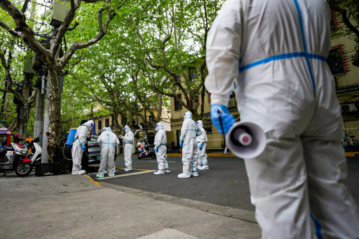 Workers in protective suits stand on a street during a lockdown in Shanghai on April 16, 2022. (Aly Song/Reuters)