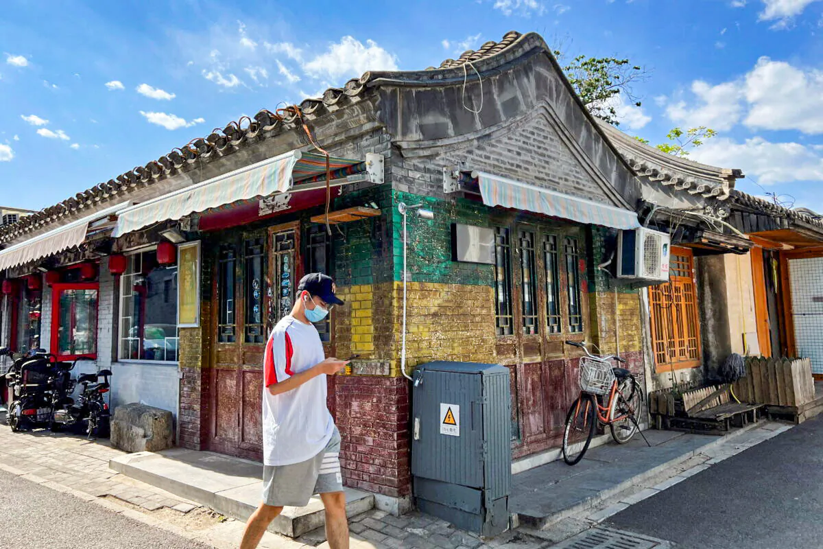 A person wearing a protective mask walks in a hutong alley in Beijing, China, on April 30, 2022. (Yew Lun Tian/Reuters)