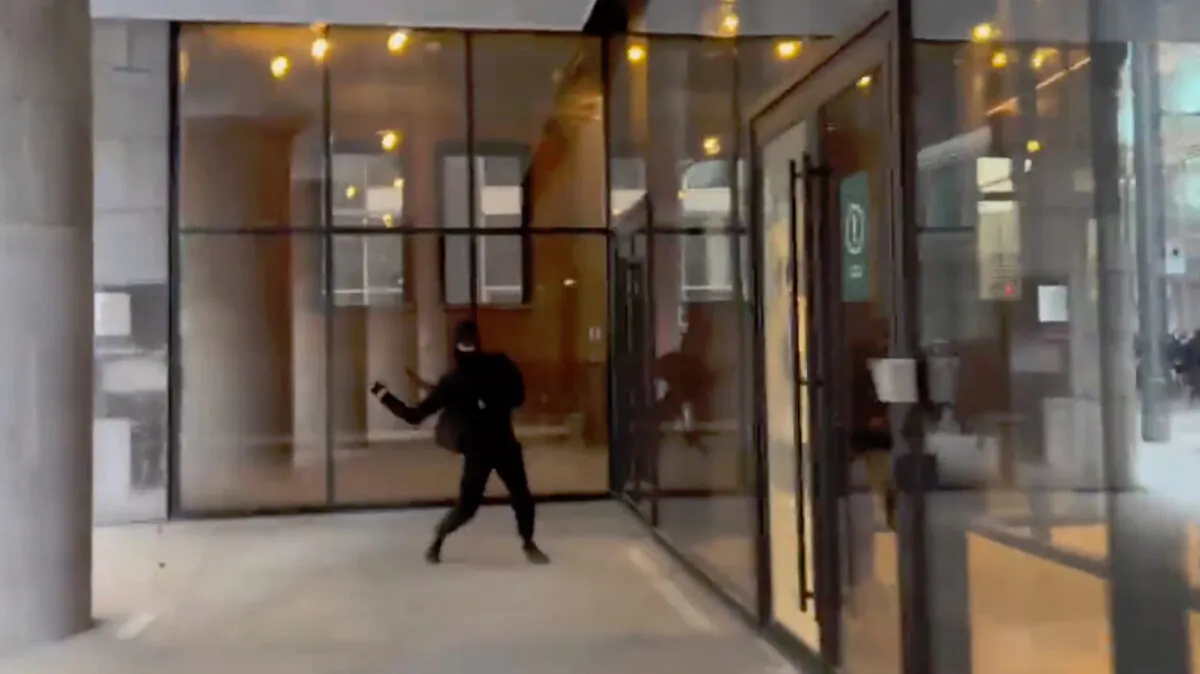 A protester throws a projectile at a window of Édifice Viger during a May Day march in Montreal on May 5, 2022. (Courtesy of Joshua Gariepy)