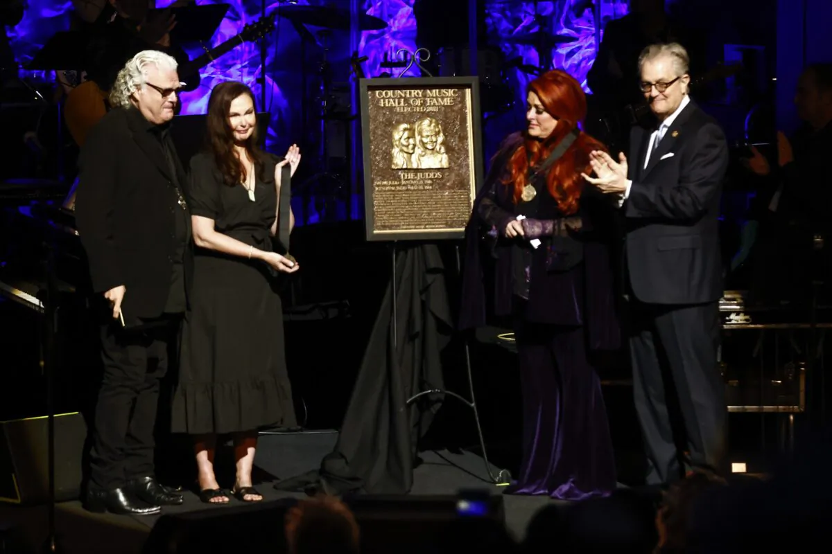 Wynonna Judd (2nd R) stands next to the Judds' induction plaque as sister Ashley Judd (L), Ricky Skaggs, and MC Kyle Young, CEO of the Country Music Hall of Fame & Museum look on during the Medallion Ceremony at the Country Music Hall of Fame in Nashville, Tenn., on May 1, 2022. (Wade Payne/Invision/AP)