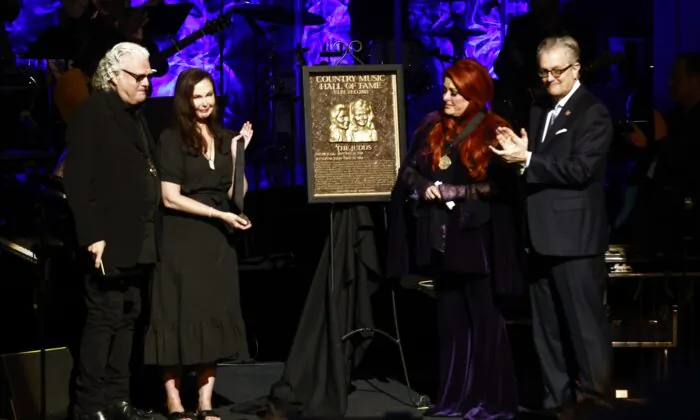 Wynonna Judd (2nd R) stands next to The Judds's induction plaque as sister Ashley Judd (L), Ricky Skaggs, and MC Kyle Young, CEO of the Country Music Hall of Fame & Museum, look on during the Medallion Ceremony at the Country Music Hall of Fame in Nashville, Tenn., on May 1, 2022. (Wade Payne/Invision/AP Photo)