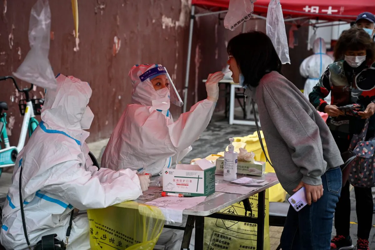 A health worker takes a swab sample from a woman to be tested for COVID-19 coronavirus at a makeshift testing site in Beijing on April 27, 2022. (Jade Gao/AFP via Getty Images)