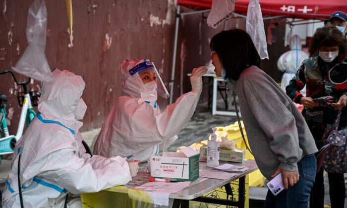 A health worker takes a swab sample from a woman to be tested for COVID-19 coronavirus at a makeshift testing site in Beijing on April 27, 2022. (Jade Gao/AFP via Getty Images)