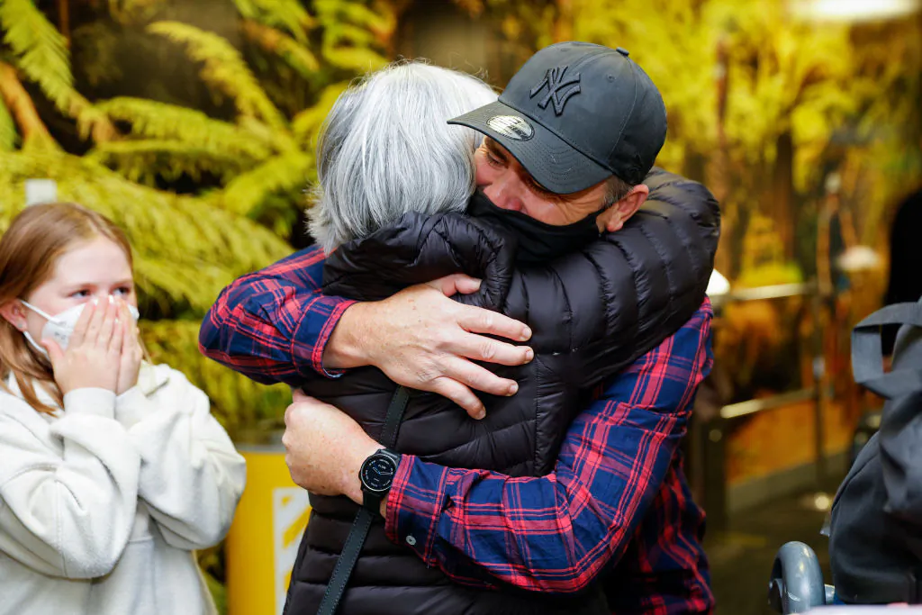 A passenger is greeted after arriving on a flight from Sydney at Wellington International Airport in Wellington, New Zealand, on April 13, 2022. (Hagen Hopkins/Getty Images)