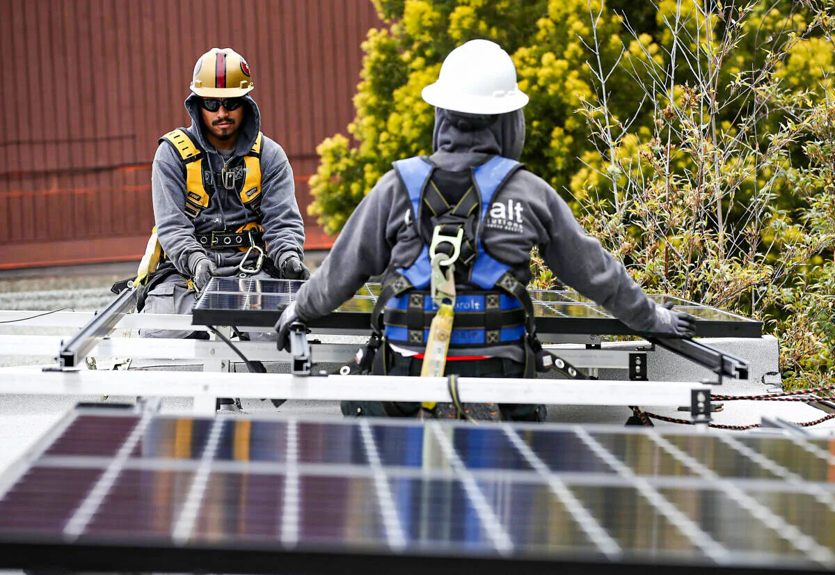 Luminalt solar installers Pam Quan (R) and Walter Morales install solar panels on the roof of a home in San Francisco, on May 9, 2018. (Justin Sullivan/Getty Images)