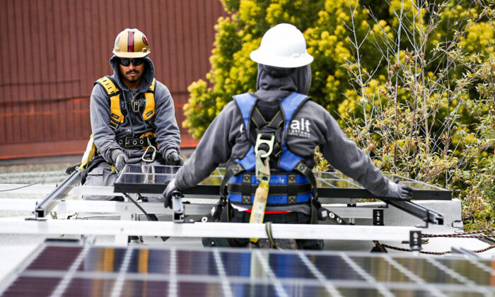 Luminalt solar installers Pam Quan (R) and Walter Morales install solar panels on the roof of a home in San Francisco, on May 9, 2018. (Justin Sullivan/Getty Images)