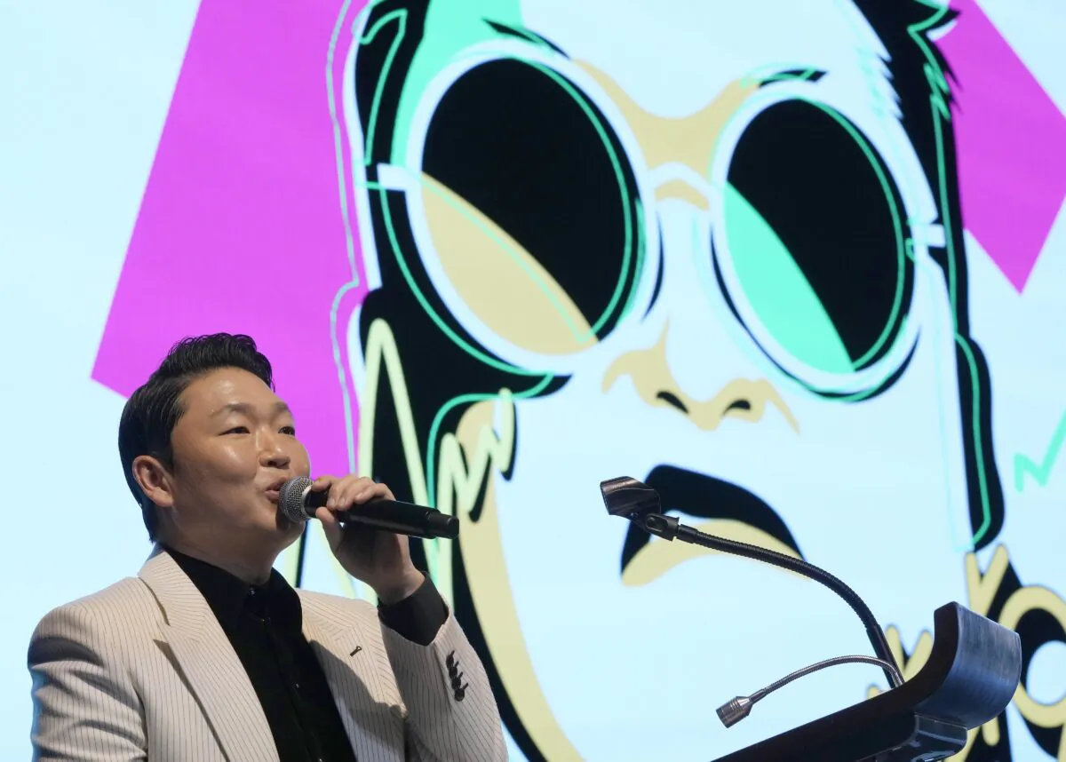 South Korean singer PSY speaks in front of his own caricature shown on the screen during a press conference to unveil his ninth full-length studio album titled "PSY 9th." in Seoul, South Korea, on April 29, 2022. (Ahn Young-joon/AP Photo)