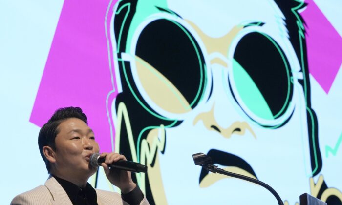 South Korean singer PSY speaks in front of his own caricature shown on the screen during a press conference to unveil his ninth full-length studio album titled "PSY 9th." in Seoul, South Korea, on April 29, 2022. (Ahn Young-joon/AP Photo)
