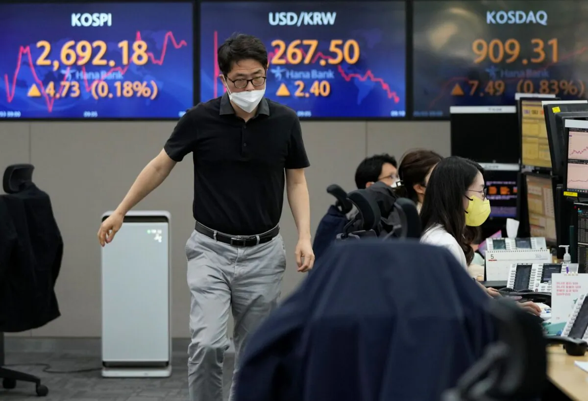 A currency trader passes by screens showing the Korea Composite Stock Price Index (KOSPI) (L), and the exchange rate of South Korean won against the U.S. dollar (C) at the foreign exchange dealing room of the KEB Hana Bank headquarters in Seoul, South Korea, on May 3, 2022. (Ahn Young-joon/AP Photo)