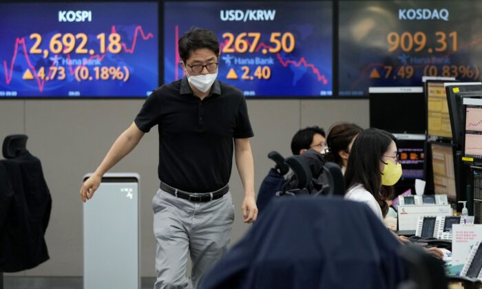 A currency trader passes by screens showing the Korea Composite Stock Price Index (KOSPI) (L), and the exchange rate of South Korean won against the U.S. dollar (C) at the foreign exchange dealing room of the KEB Hana Bank headquarters in Seoul, South Korea, on May 3, 2022. (Ahn Young-joon/AP Photo)