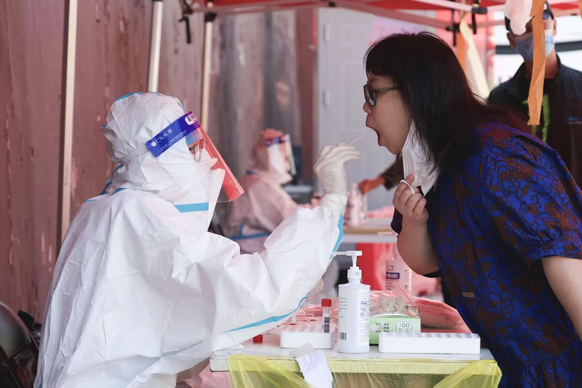A health worker takes a swab sample from a woman to be tested for the COVID-19 coronavirus at a swab collection site in Beijing, China, on May 3, 2022. (NOEL CELIS/AFP via Getty Images)