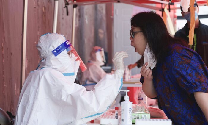 A health worker takes a swab sample from a woman to be tested for the COVID-19 coronavirus at a swab collection site in Beijing, China, on May 3, 2022. (NOEL CELIS/AFP via Getty Images)