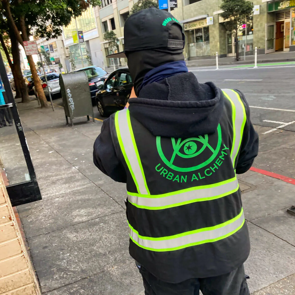 A person in an Urban Alchemy jacket stands on a San Francisco street on Jan. 5, 2022. (Steve Ispas/The Epoch Times)