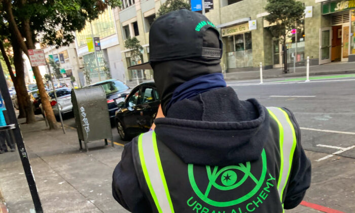 A person in an Urban Alchemy jacket stands on a San Francisco street on Jan. 5, 2022. (Steve Ispas/The Epoch Times)