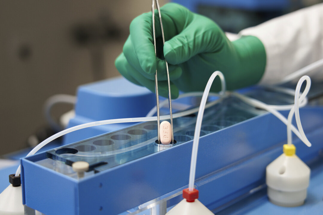 A Pfizer technician handles the company's COVID-19 pill, known as Paxlovid, in a file photograph. (Pfizer via AP)
