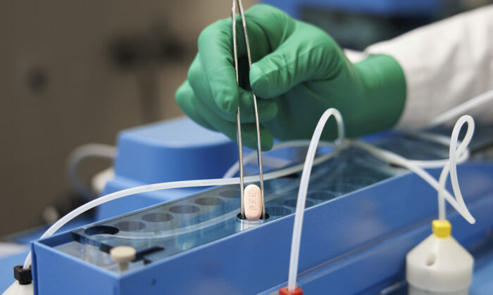 A Pfizer technician handles the company's COVID-19 pill, known as Paxlovid, in a file photograph. (Pfizer via AP)
