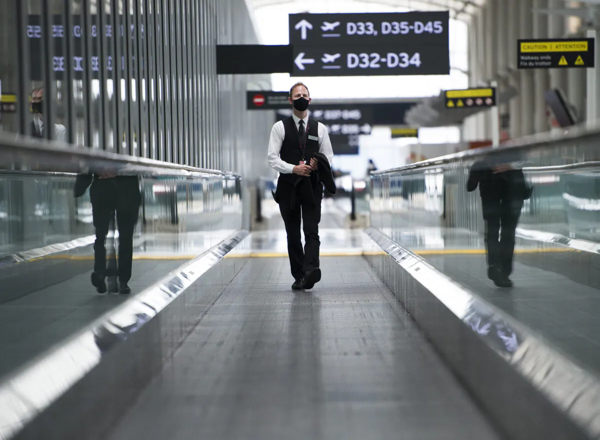 A man rides a escalator wearing mandatory masks at Toronto's Pearson International Airport in Toronto on June 23, 2020. (The Canadian Press/Nathan Denette)
