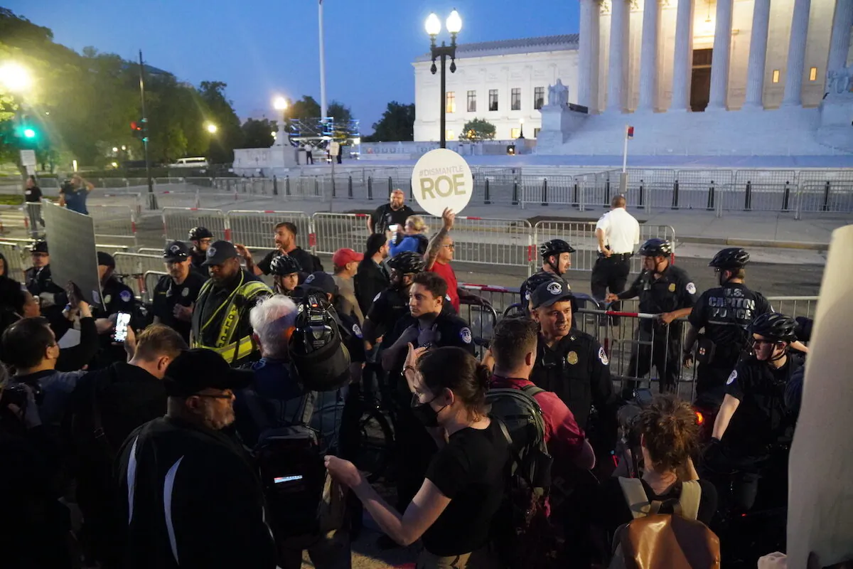 A.J. Hurley (rear left), Rev. Patrick Mahoney (rear left center), Pastor Mark Lee Dickson (rear right center), and Bryan Kemper(rear right), stand in front of the Supreme Court while surrounded by police and protestors on May 4, 2022. (Jackson Elliott/The Epoch Times)