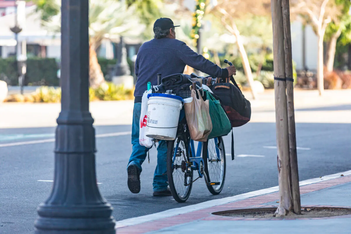 A homeless man walks with his bike and posessions in Santa Ana, Calif., on Dec. 17, 2020. (John Fredricks/The Epoch Times)